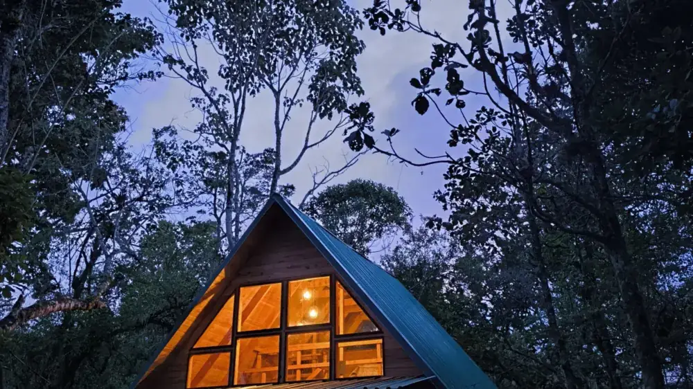 Chata A-frame nocą w zaśnieżonym lesie